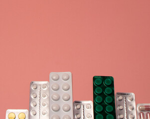 White pills in a blister on a pink background. Medical pharmacy concept
