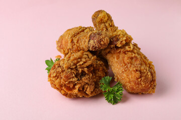 Tasty fried chicken on pink background, close up