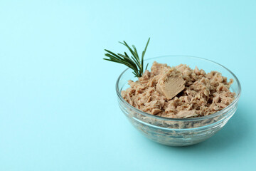 Glass bowl with canned tuna on blue background