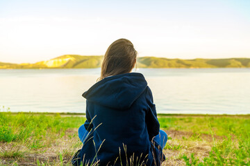 Little teen girl sad sitting in nature, the concept of teenage problems and mental health