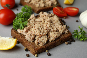 Sandwiches with canned tuna and ingredients on gray background