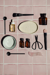Creative flat lay composition of natural eco-friendly cosmetic products and accessories on a pink bathroom tile countertop background. Beauty routine.
