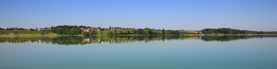 Idyllic rural landscape reflecting in Lake Pfaffikon, Pfaeffikon. Old village Seegraben, Seegraeben. Calm spring morning in Zurich Canton, Switzerland.