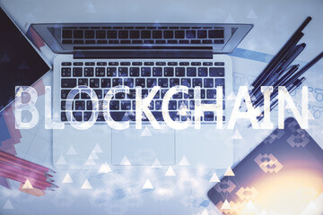 Blockchain theme hologram drawings over computer on the desktop background. Top view. Multi...