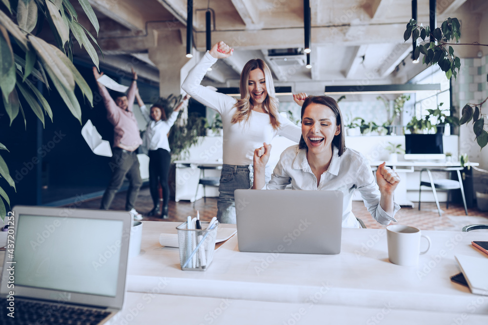 Wall mural Two young happy businesswomen celebrating project success in office