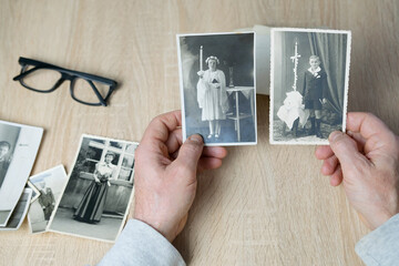 male hand holding old vintage monochrome photographs of children 1940 - 1950 in sepia color are...