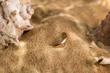 golden ring underwater on the sand next to the seashells
