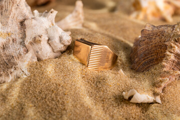 golden ring underwater on the sand next to the seashells