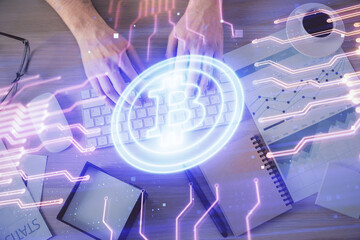 Double exposure of man's hands typing over computer keyboard and crypto currency theme hologram...