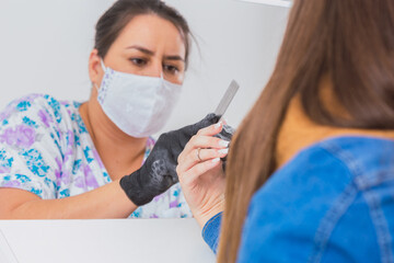 Professional manicurist working on the hands of a young woman in the salon.