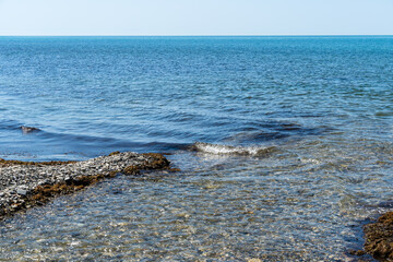 Mouth of mountain river Teshebs in Arkhipo-Osipovka. Close-up. Clear waters of  Teshebs River flow into salty emerald waters of Black Sea. Clear horizon line is visible.