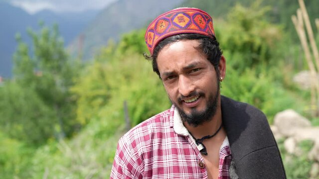 close up shot of a young indian male himachali man standing outdoors looking at camera and smiling in a broad daylight