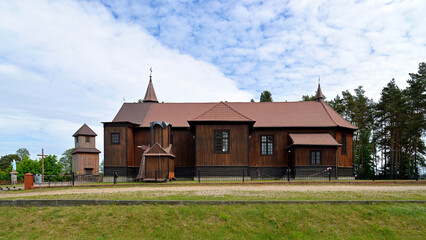 Obraz premium Built in 1925, a historic wooden Catholic church dedicated to Saint Roch in the village of Leman in Podlasie, Poland. There is also a historic wooden belfry next to the church.