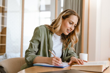 Portrait of pleased blond woman writing down notes