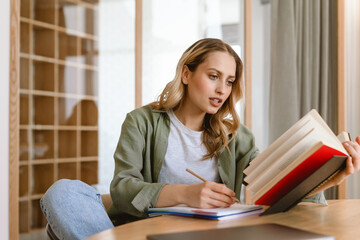 Portrait of pleased blond woman writing down notes
