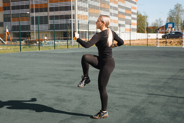 Fototapeta na wymiar Street workout, healthy active lifestyle. Fitness young woman warming up before training outdoors. Sportswoman in black tight sports suit training on the playground.