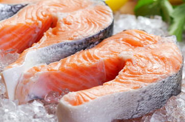 close-up view of salmon steaks on ice with greens and lemon