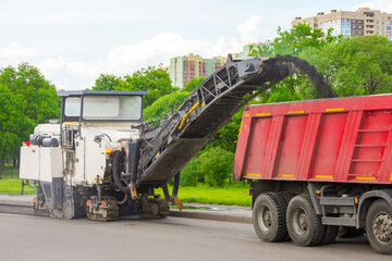 Road cold milling machine removes the old asphalt and loading into a dump truck. Repair of asphalt...
