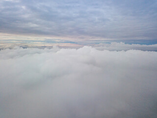 Obraz premium Aerial high flight above the clouds. The rays of the rising sun break through the clouds.