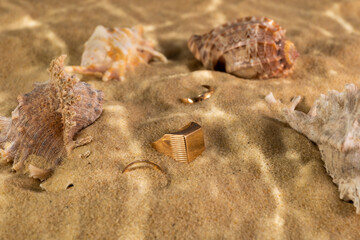 golden ring underwater on the sand next to the seashells