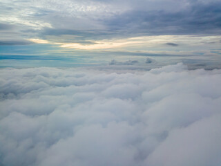 Aerial high flight above the clouds. The rays of the rising sun break through the clouds.