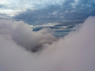 Aerial high flight above the clouds. The rays of the rising sun break through the clouds.