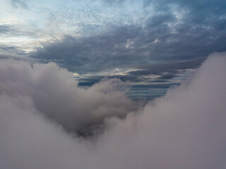 Aerial high flight above the clouds. The rays of the rising sun break through the clouds.