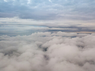 Aerial high flight above the clouds. The rays of the rising sun break through the clouds.