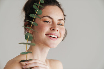 Half-naked brunette woman smiling while posing with eucalyptus © Drobot Dean