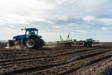 Obraz premium A tractor with seedbed cultivator ploughs field on morning.