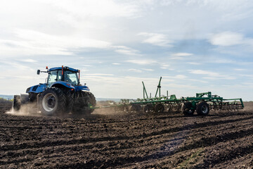 Obraz premium A tractor with seedbed cultivator ploughs field on morning.