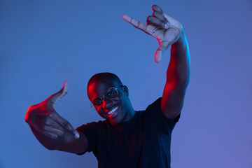 Portrait of young African handsome man posing isolated over dark background in mixed neon light.