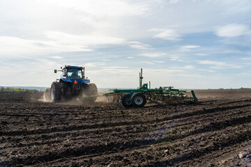 A tractor with cultivator plowing on morning.