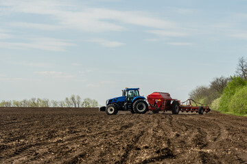 Fototapeta premium A tractor cultivating field at spring morning.