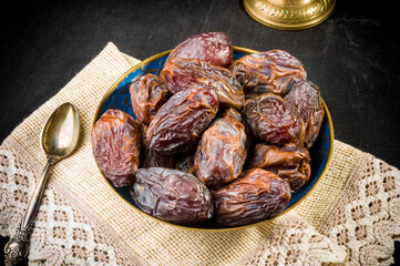 Big luxury dried date fruit in bowls on a linen napkin, kurma ramadan kareem concept, close up.