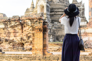 Fototapeta na wymiar Asian female tourists taking pictures at Wat Phra Si Sanphet, Phra Nakhon Si Ayutthaya, Thailand.