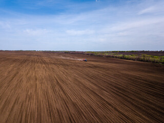 Obraz premium Aerial view of plowing fields by tractor and blue sky