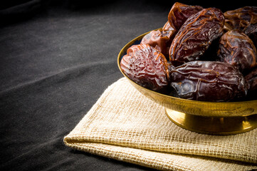 Big luxury dried date fruit in bowls on a linen napkin, kurma ramadan kareem concept, close up.