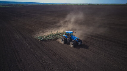 Obraz premium Aerial image of a tractor with seedbed cultivator ploughs field