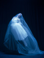 Young graceful balerina in image of ghost bride in art performance isolated on dark background in neon light. © Lustre Art Group 