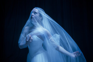 Young graceful balerina in image of ghost bride in art performance isolated on dark background in neon light. © Lustre Art Group 