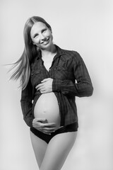 schwangere Frau zeigt ihren nackten Babybauch und lächelt