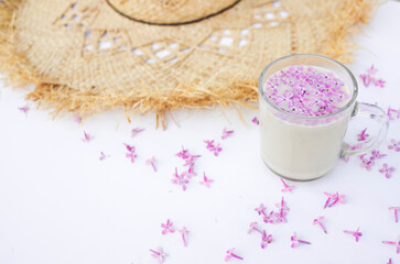 Obraz na płótnie Canvas Cup of hot morning coffee, lilac petals and straw hat on a white background. Copy space for text. The concept of vacation and good morning wishes.
