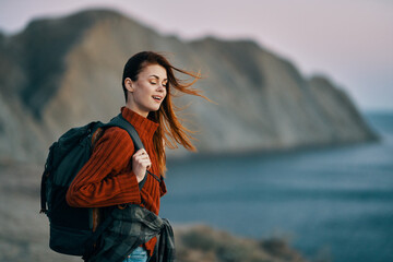 portrait of a beautiful woman in the mountains near the sea and a backpack on her back