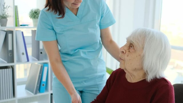 Senior Woman Sitting Next To Elderly Care Nurse At Home