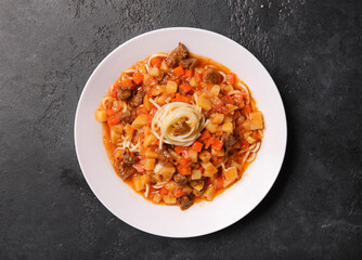 pasta, meat and sauce in a white plate on a dark background, Caucasian Asian cuisine