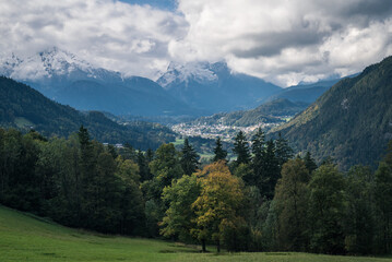 Beautiful alpine mountain valley with a forest of trees and cloudy sky in the background in Austria.