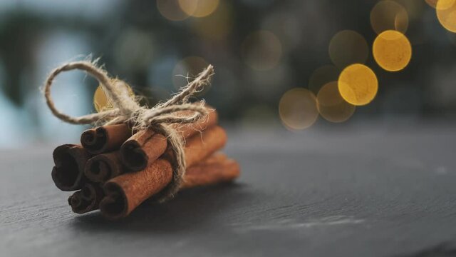 Dried cinnamon rolled in sticks and tied with rope on dark background