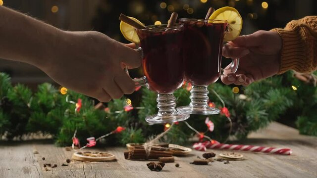 Couple clinking glasses with festive mulled wine on christmas tree background