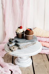 Delicious chocolate muffins with raspberry, blueberry and strawberry cream. Copy space. Set of various delicious muffins on a tray.